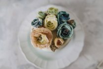 Свадебный торт с голубыми и бежевыми цветами из сливочного масла на белой тарелке — стоковое фото