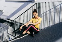 Donna etnica sportiva seduta sulle scale — Foto stock