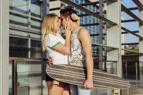 Casal com skate na frente do edifício — Fotografia de Stock
