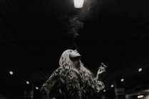 Mujer pelirroja bonita teniendo humo en el estacionamiento borroso. - foto de stock