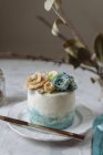 Gâteau de mariage avec des fleurs de crème au beurre bleu et beige sur plaque blanche — Photo de stock