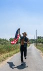 Человек бегущий с американским флагом — стоковое фото