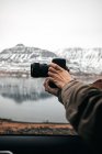 Vista lateral do fotógrafo profissional da colheita tirando fotos com câmera no lago em colinas na Islândia — Fotografia de Stock