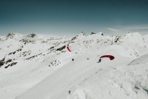 Turistas con paracaídas de pie en la ladera nevada - foto de stock