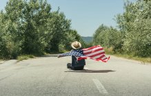 Mann mit amerikanischer Flagge sitzt auf Straße — Stockfoto