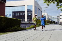 Hommes ethniques jogging ensemble sur la rue moderne — Photo de stock
