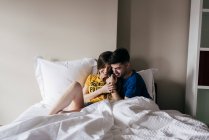 Sorridente coppia sdraiata a letto — Foto stock