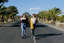 Женщины идут по солнечной дороге — стоковое фото