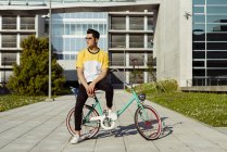 Молодой человек, сидящий на винтажном велосипеде — стоковое фото