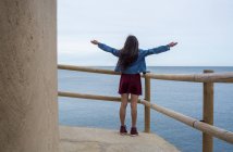 Girl standing at handrail at seaside — Stock Photo