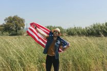 Mann mit amerikanischer Flagge steht im Feld — Stockfoto