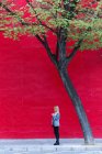 Geschäftsfrau fährt mit Handy gegen rote Wand — Stockfoto
