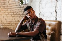 Negro hombre sentado en la cafetería - foto de stock