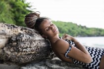 Frau im Badeanzug auf Baumstamm liegend — Stockfoto