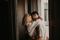 Zärtliches Paar umarmt sich am Fenster — Stockfoto