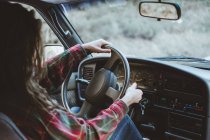 Mujer irreconocible bastante joven conduciendo un coche en la naturaleza - foto de stock
