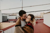 Casal abraçando com cobertor em um terraço — Fotografia de Stock