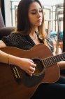 Вдумчивая молодая женщина играет на гитаре — стоковое фото