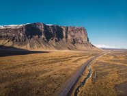 Estrada vazia na natureza com penhasco rochoso no fundo na Islândia — Fotografia de Stock