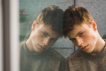 Sinnlicher junger Mann mit Sommersprossen lehnt am Fenster — Stockfoto