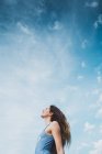 Расслабленная молодая женщина в голубом купальнике стоит на фоне голубого неба — стоковое фото