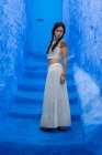 Задумчивая женщина стоит на голубой лестнице — стоковое фото