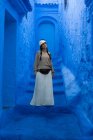 Woman wearing cap and long skirt walking on Moroccan city dyed blue — Stock Photo