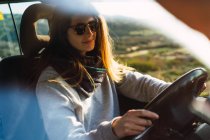 Woman in sunglasses driving car in nature — Stock Photo