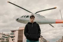 Красивий молодий чоловік стоїть біля пам'ятника вертольоту на міській вулиці — стокове фото