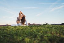 Жінка розтягується і робить йогу на газоні в природі — стокове фото