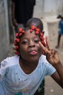 ANGOLA - AFRICA - APRIL 5, 2018 - Ethnic girl showing peace gesture and grimacing with tongue out outdoors — Stock Photo
