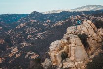 Frau sitzt auf Felsen in den Bergen und blickt auf die Aussicht — Stockfoto
