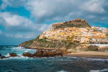 Pequena cidade com edifícios coloridos na colina rochosa à beira-mar, Sardenha, Itália — Fotografia de Stock
