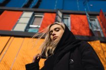 Attraktive blonde Frau blickt in Kamera gegen buntes Gebäude — Stockfoto