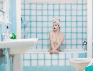 Sensual young with towel on head sitting in bathtub — Stock Photo