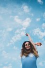 Allegra giovane donna in costume da bagno blu in piedi contro il cielo blu — Foto stock