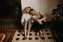 Lächelnder Mann und Frau, die zu Hause zusammen auf dem Boden sitzen — Stockfoto