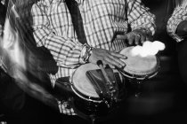 Обрезанный музыкант, играющий на барабанах в ночном клубе, черно-белый кадр с длительной экспозицией — стоковое фото