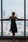 Woman in dress standing in apartment with city view — Stock Photo