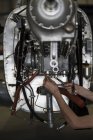 Hände eines Flugzeugmechanikers reparieren Motor eines Kleinflugzeugs im Hangar — Stockfoto