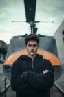 Young man standing with arms crossed with helicopter monument on background — Stock Photo