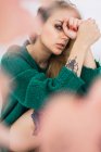 Sinnliche junge Frau mit Tätowierungen im grünen Pullover und Blick in die Kamera — Stockfoto