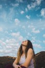 Sensual mujer sentada en la naturaleza bajo el cielo azul - foto de stock