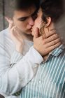 Blick aus dem Fenster auf junge Männer und Frauen im Pyjama, die stehen und sich küssen — Stockfoto