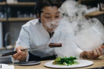 Chef cooking in restaurant with smoke dish — Stock Photo