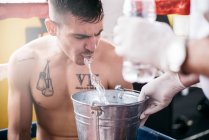 Boxer sportsman in the ring spitting the water to the bucket. — Stock Photo