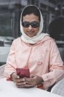 Mulher marroquina com hijab e vestido árabe tradicional usando telefone celular no café — Fotografia de Stock