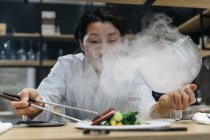 Chef cooking in restaurant with smoke dish — Stock Photo