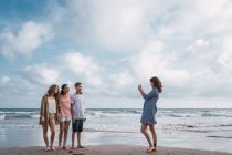 Donna che fotografa bambini con smartphone sulla spiaggia — Foto stock