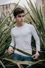 Hübsche junge modische Teenager stehen im grünen Busch — Stockfoto